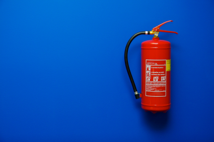 a red fire extinguisher hanging on a blue wall