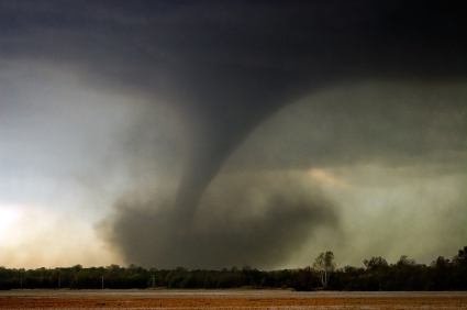 a dark tornado zooming across a field