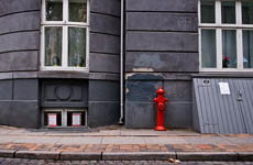a sidewalk in front of a dark gray building and red fire hydrant