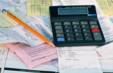 A calculator and number two pencil sitting on top of multiple receipts and papers to illustrate the process of budgeting.