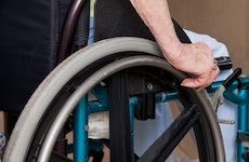 Person sitting in wheelchair, one hand on wheel