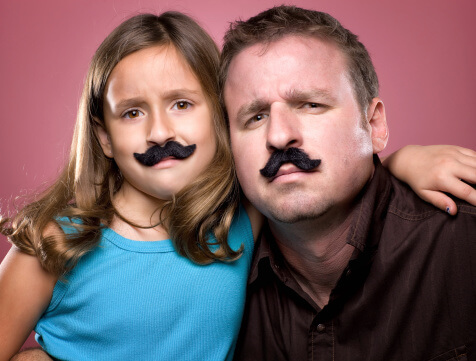 Father and daughter wearing mustaches and being silly on Father's Day