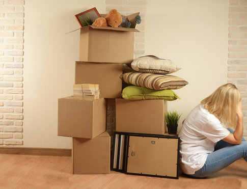 Stack of moving boxes and blonde woman with head in hands, stressed