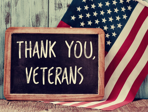 Chalkboard sign saying, "Thank you, veterans," in front of American flag