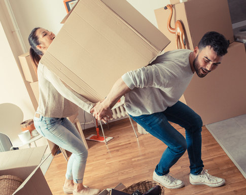 Young man and woman lifting a moving box, getting ready to move into temporary furnished apartment