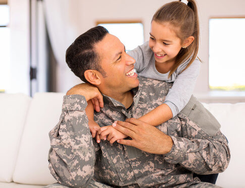 Father in military uniform and young daughter happily hugging