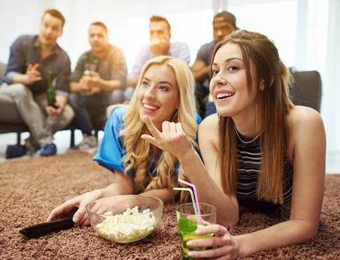 Group of young friends watching football game in living room