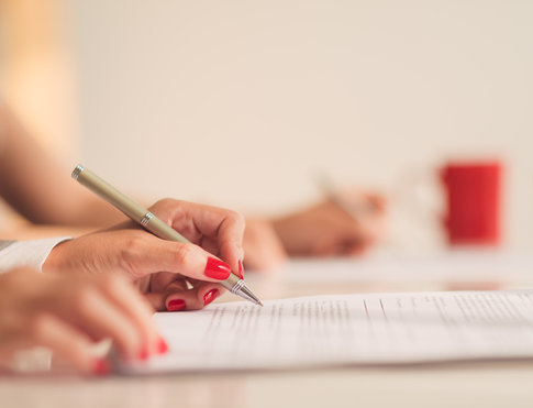 Woman with red fingernails, signing paperwork to renew her apartment lease