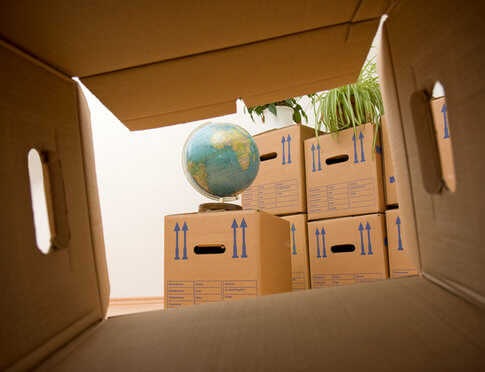 Looking through cardboard moving box at globe, packing for international move