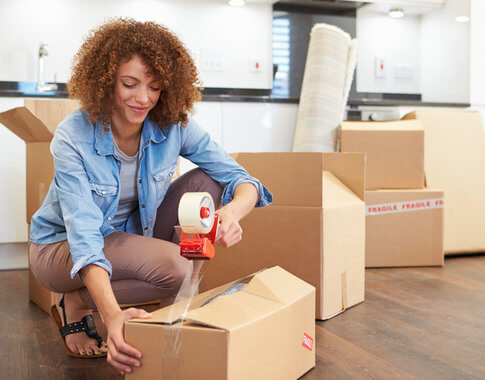 African American woman packing cardboard boxes, prepping for apartment move