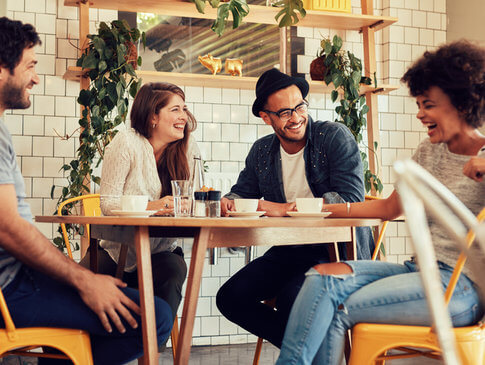 Four friends enjoying each other's company and laughing around table