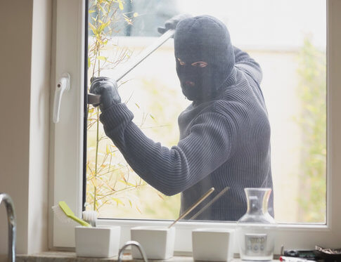 Masked burglar attempting to break into apartment kitchen with crow bar