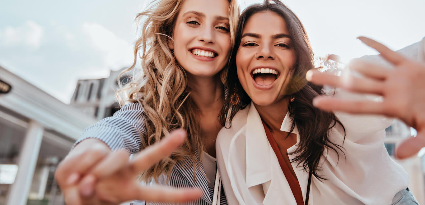 Two young women smile and pose for the camera happily.