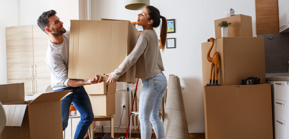 A couple carries a large box together as they move out of their home.