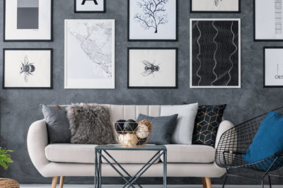 A modern living room with charcoal walls and a gallery wall featuring art prints in various sizes.