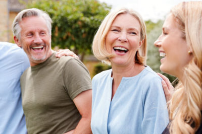 Two older parents stand in laughter among their adult children.