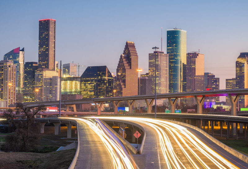Skyline shot of Houston, Texas at dusk with headlights blurring on interstate.