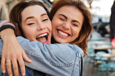 Two sisters embrace in joy on the city street.