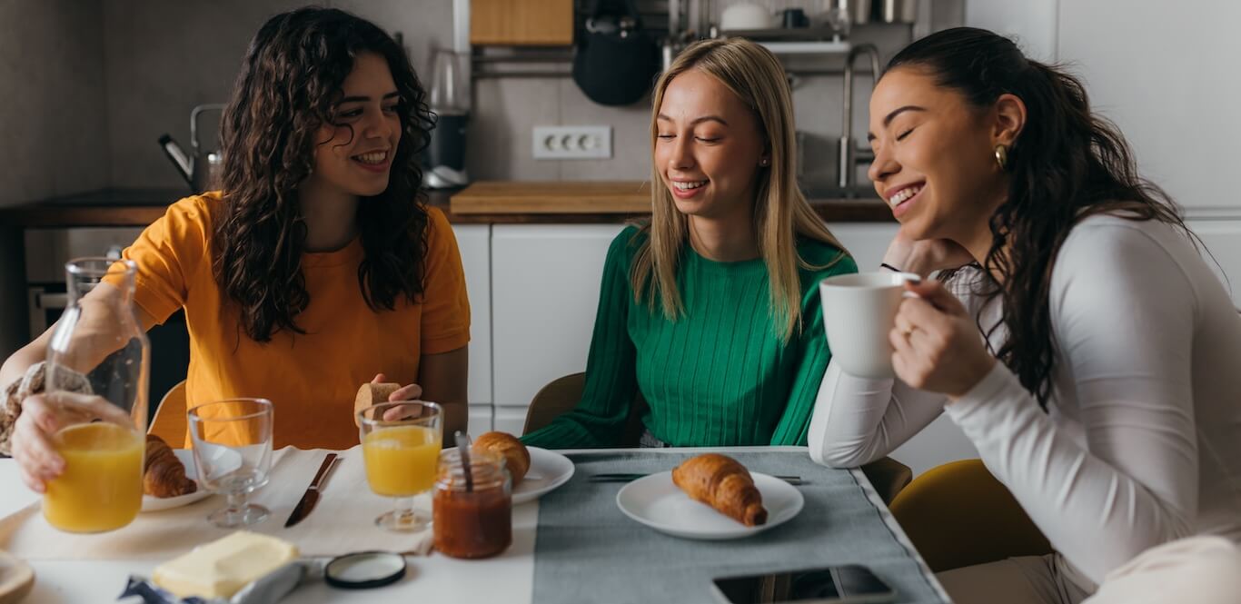 Three female roommates having breakfast together.