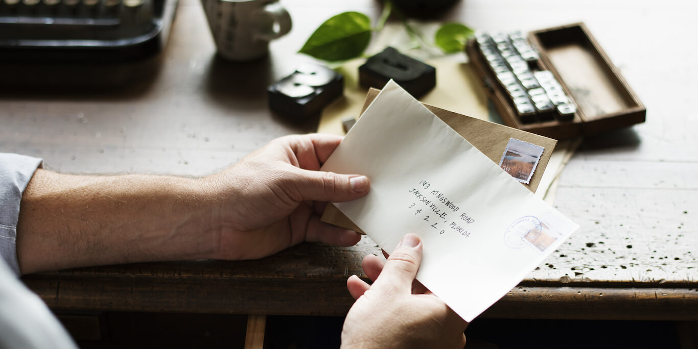 A man holds an envelope at his desk.