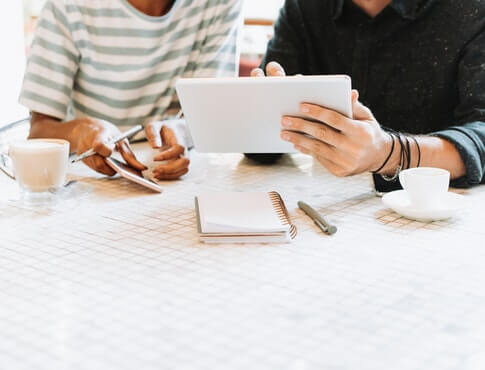 friends splitting costs at coffee shop using tablet