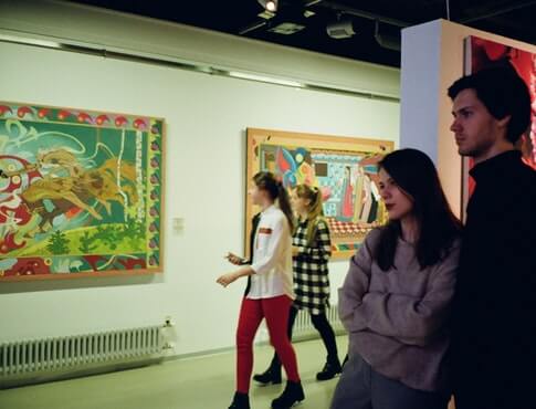 couple looking at art exhibit with other people in the background