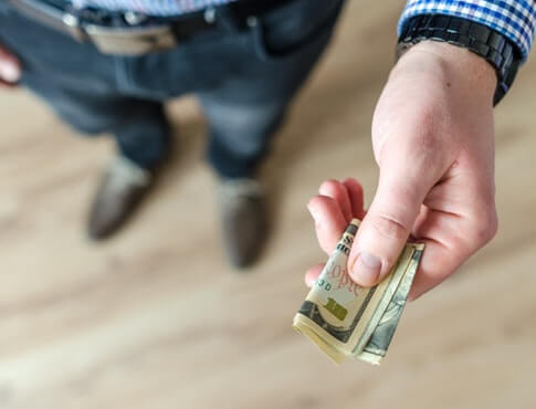 man handing over folded dollar bills