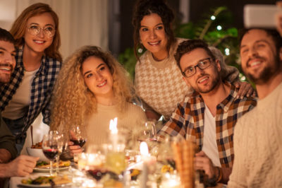 Group of friends takes a selfie at the table in front of a spread of holiday decor and food.