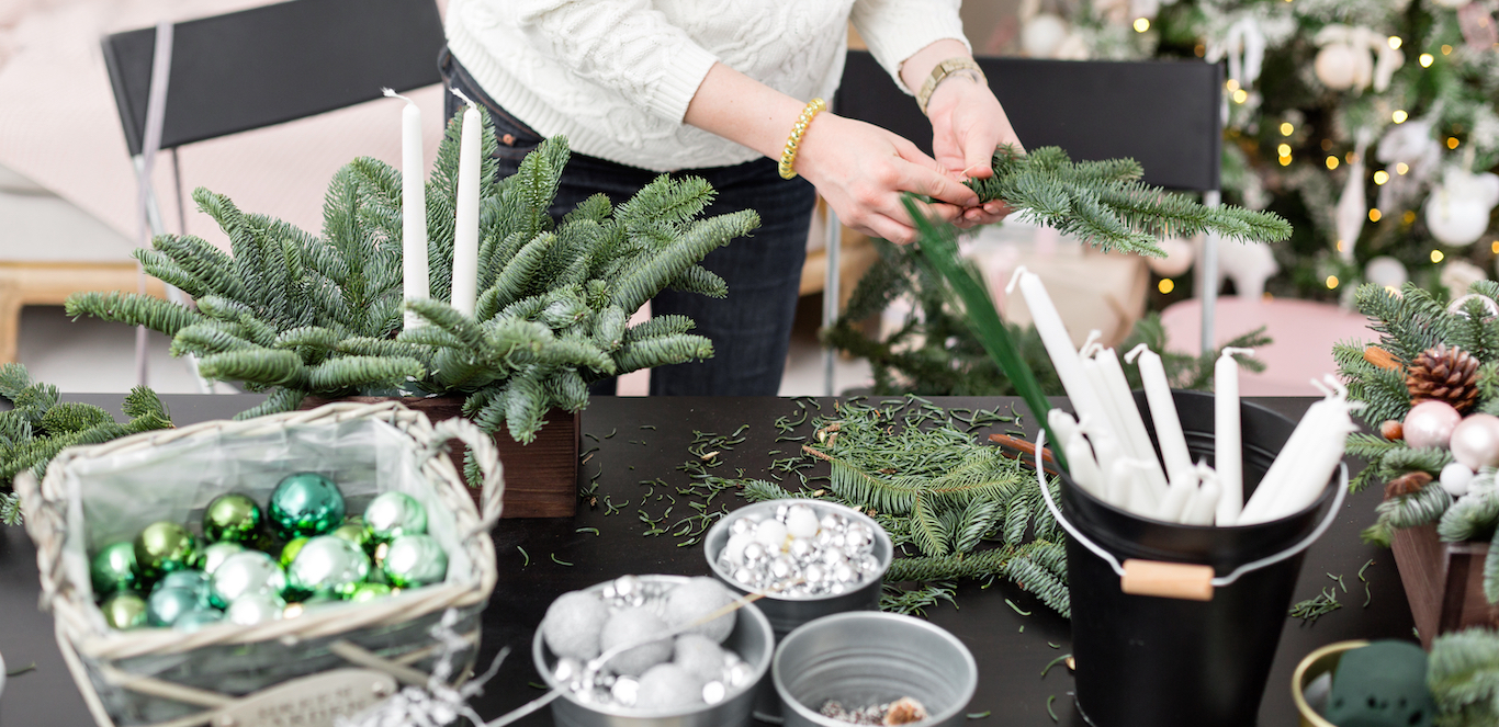 A woman in a cream sweater is organizing holiday decor to put into storage.