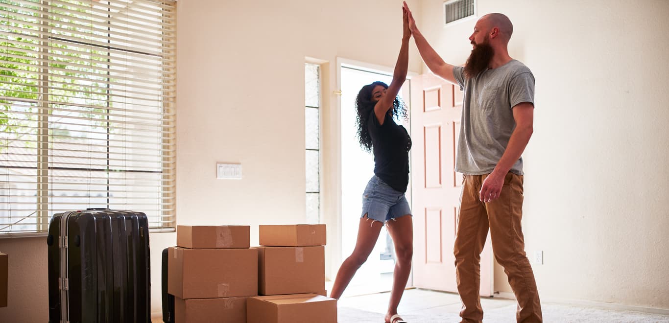 Couple that have just moved into a new apartment smiling and high-fiving.