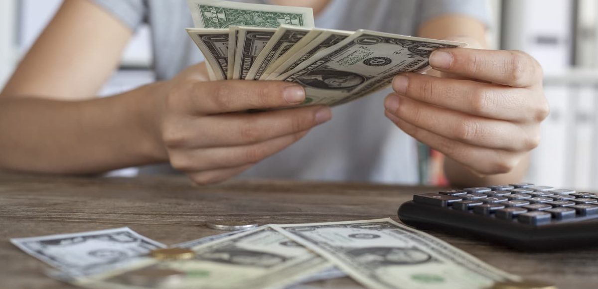 Woman counting American dollars at desk