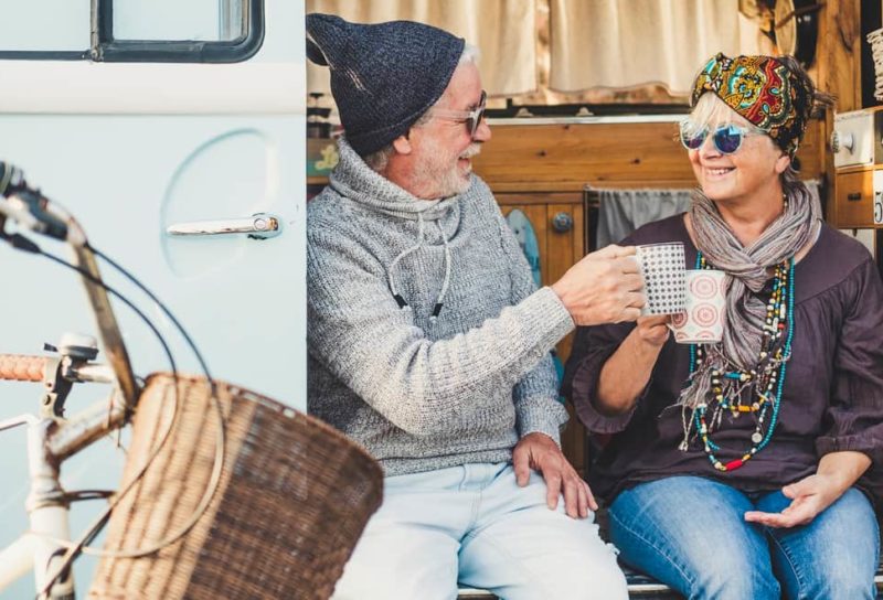 Mature couple sitting in entryway of their tiny home/RV.