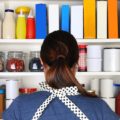 Woman in black and white polka-dot apron staring into kitchen pantry.
