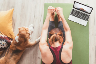 Woman doing yoga and stretching in her apartment after creating an apartment home gym.