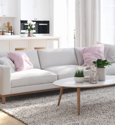 Modern living room with light gray and white pallet and pink accents faux plants in furnished apartment for rent near me.