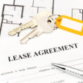 Lease agreement form with house keys and pen on top of it