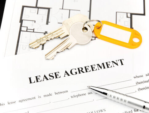 Lease agreement form with house keys and pen on top of it