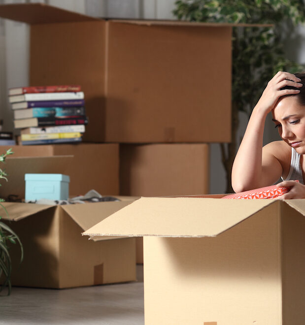 Woman sitting on floor amongst moving boxes