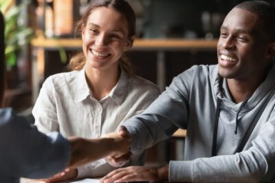 A young couple shaking hands with a leasing agent.