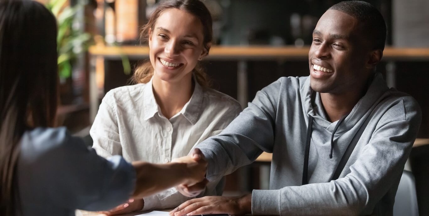 A young couple shaking hands with a leasing agent.