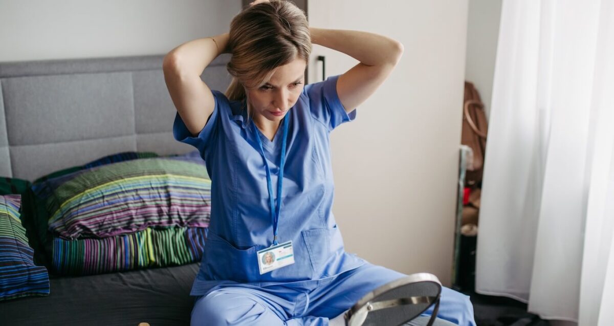 A travel nurse getting ready for the day, fixing her hair.